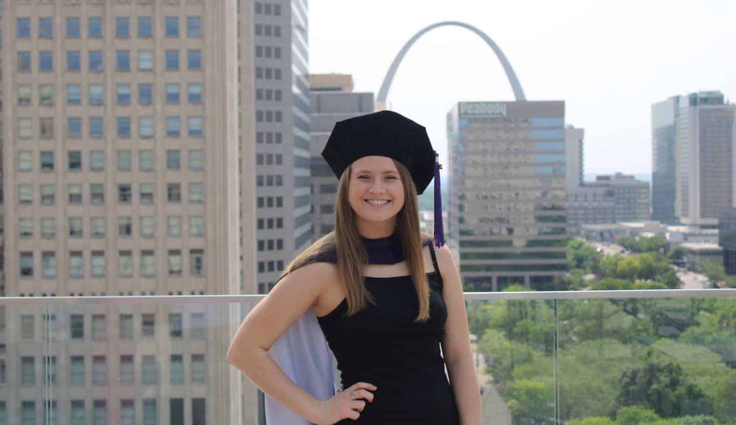 Jenna DeBarry in a graduation cap with the St. Louis skyline behind her.